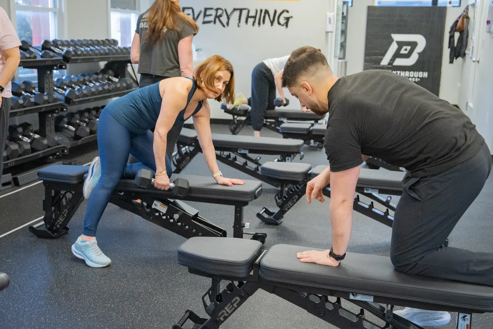 Breakthrough coach guiding a member through a dumbbell row